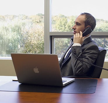 Man on phone and laptop at a desk