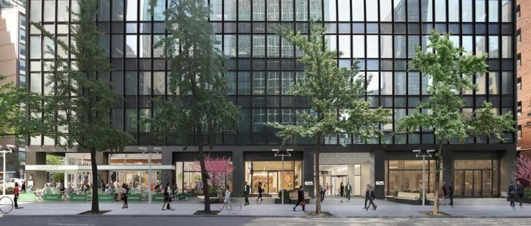 Street view of a modern glass building with trees and people walking on the sidewalk.