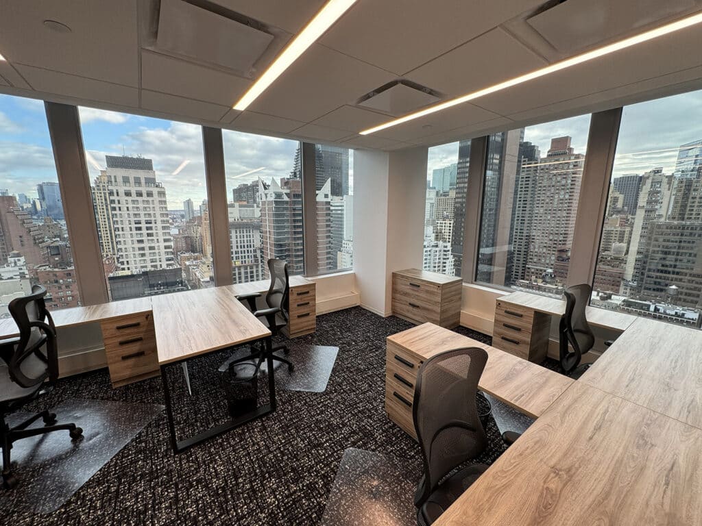 Modern office with wooden desks and chairs, large windows, and a city skyline view.