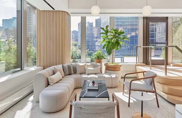 Modern living room with a curved sofa, indoor plant, large windows, and cityscape views in the background.