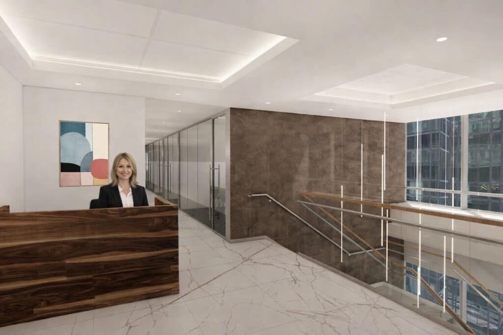 A woman sits at a wooden reception desk in a modern office with marble floors and glass walls.