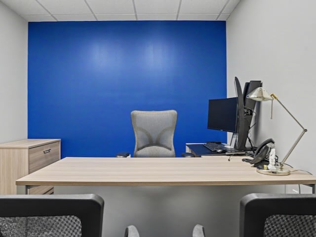 Modern office with a desk, chair, computer monitors, lamp, and blue accent wall in the background.