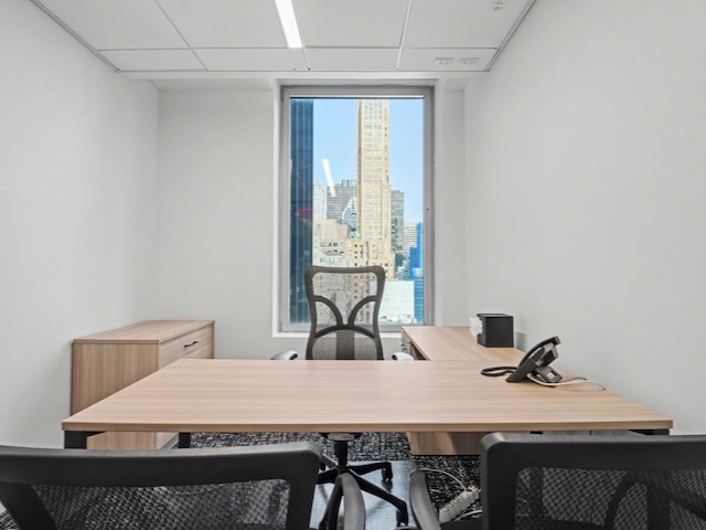 Modern office with three chairs, a desk, phone, and window showing tall city buildings outside.