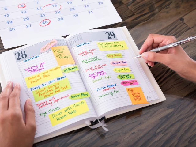 Close-up Of A Businesswoman Making Agenda On Diary At Workplace